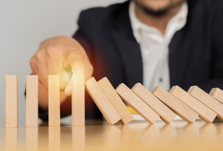 A man sitting and watching a chain of falling dominoes.