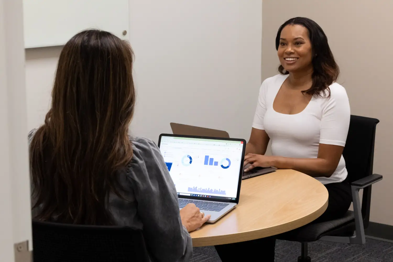 Procurement manager in a meeting with a supplier, using financial data on her laptop to renegotiate pricing terms