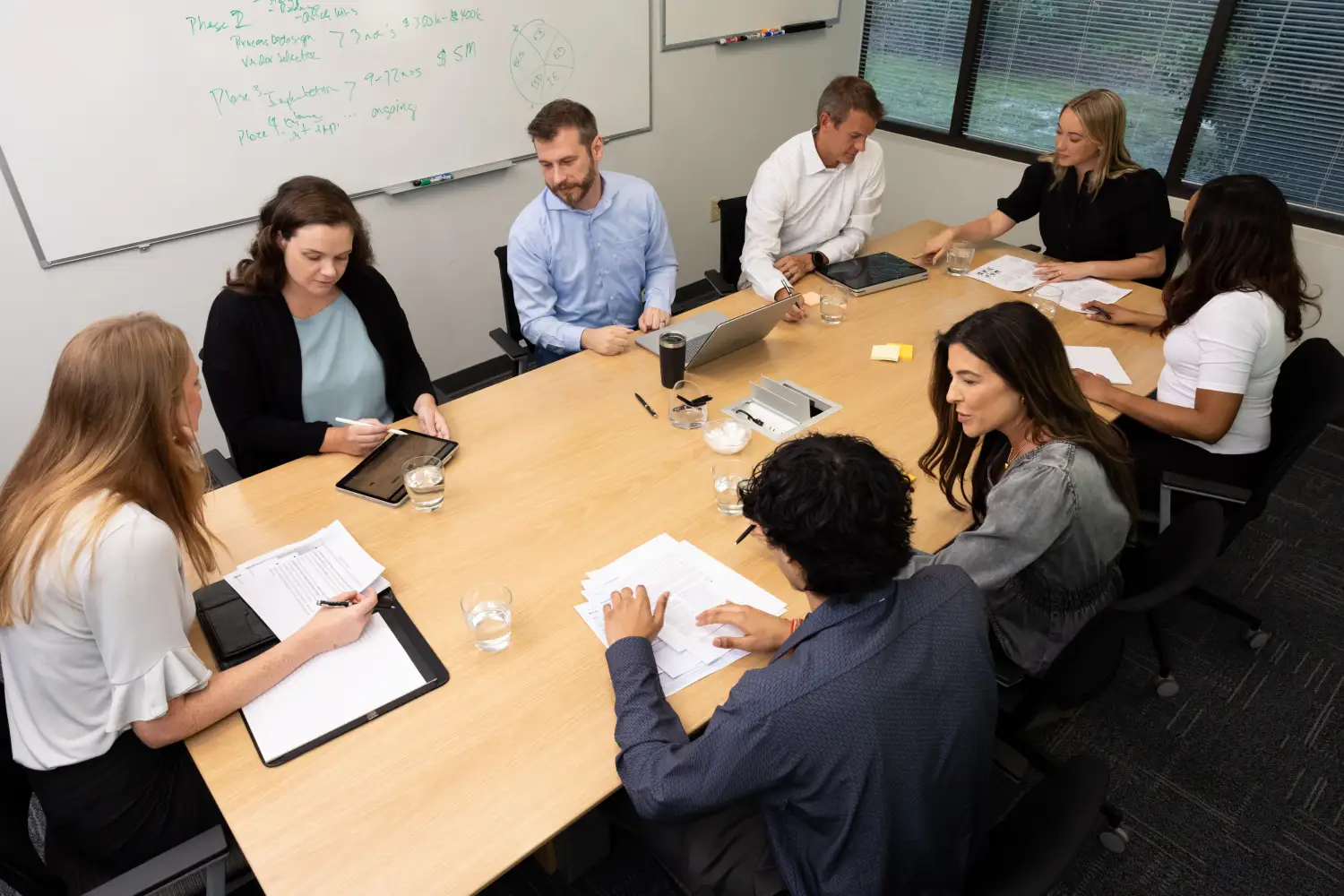 Image of department heads in a meeting, using consolidated data on their gadgets to arrive at data-driven decisions