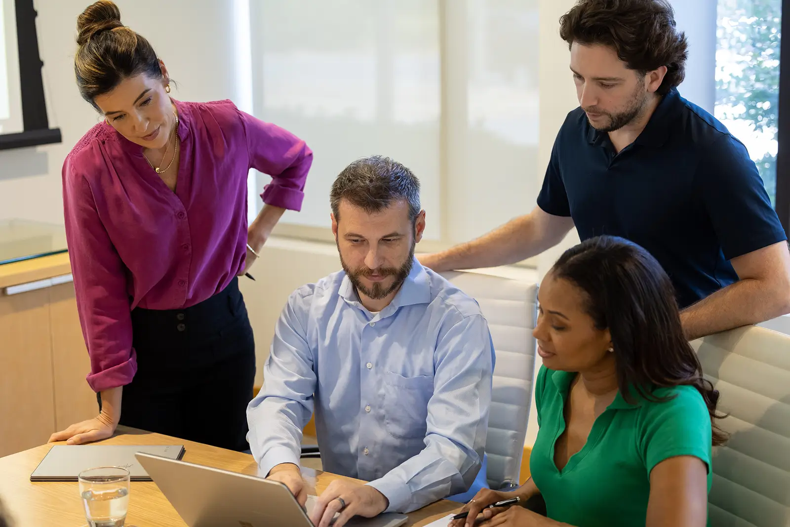 Finance and sales team members discussing a customer lifecycle at a shared desk in a collaborative work environment.